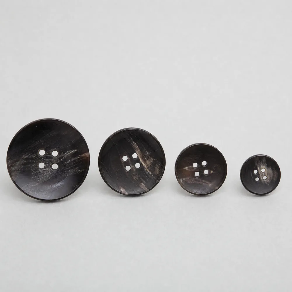 Four dark horn buttons with natural mottled grain, arranged in a row.