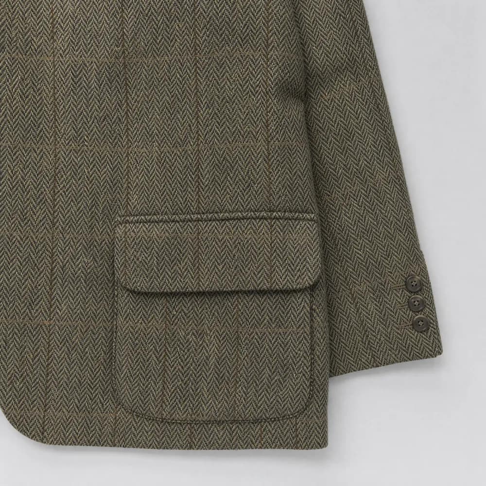 A flapped hip pocket on a tweed jacket, the flap lying over the pocket mouth.