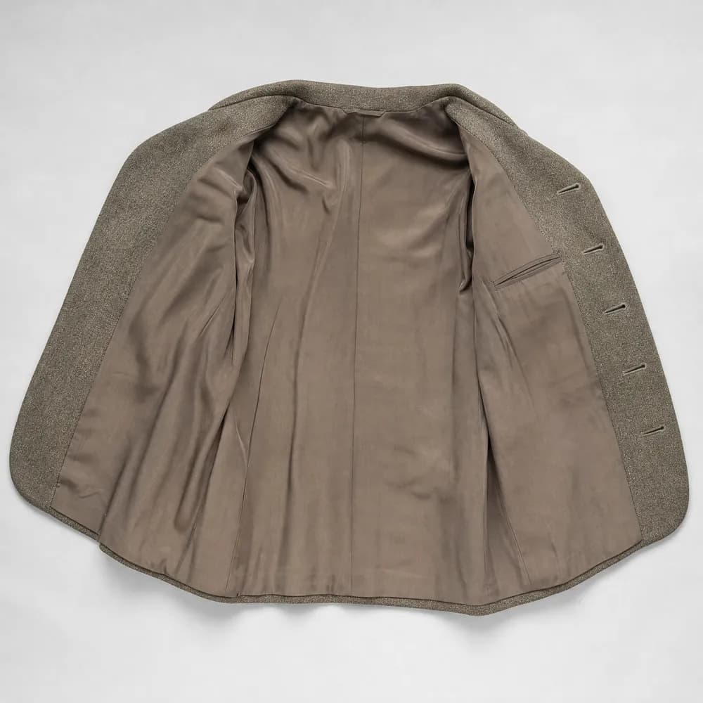The inside of a jacket opened flat, showing the lining, an interior pocket and a felled seam.