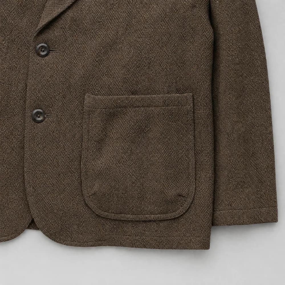 A topstitched patch pocket on a tweed jacket, photographed flat from above.