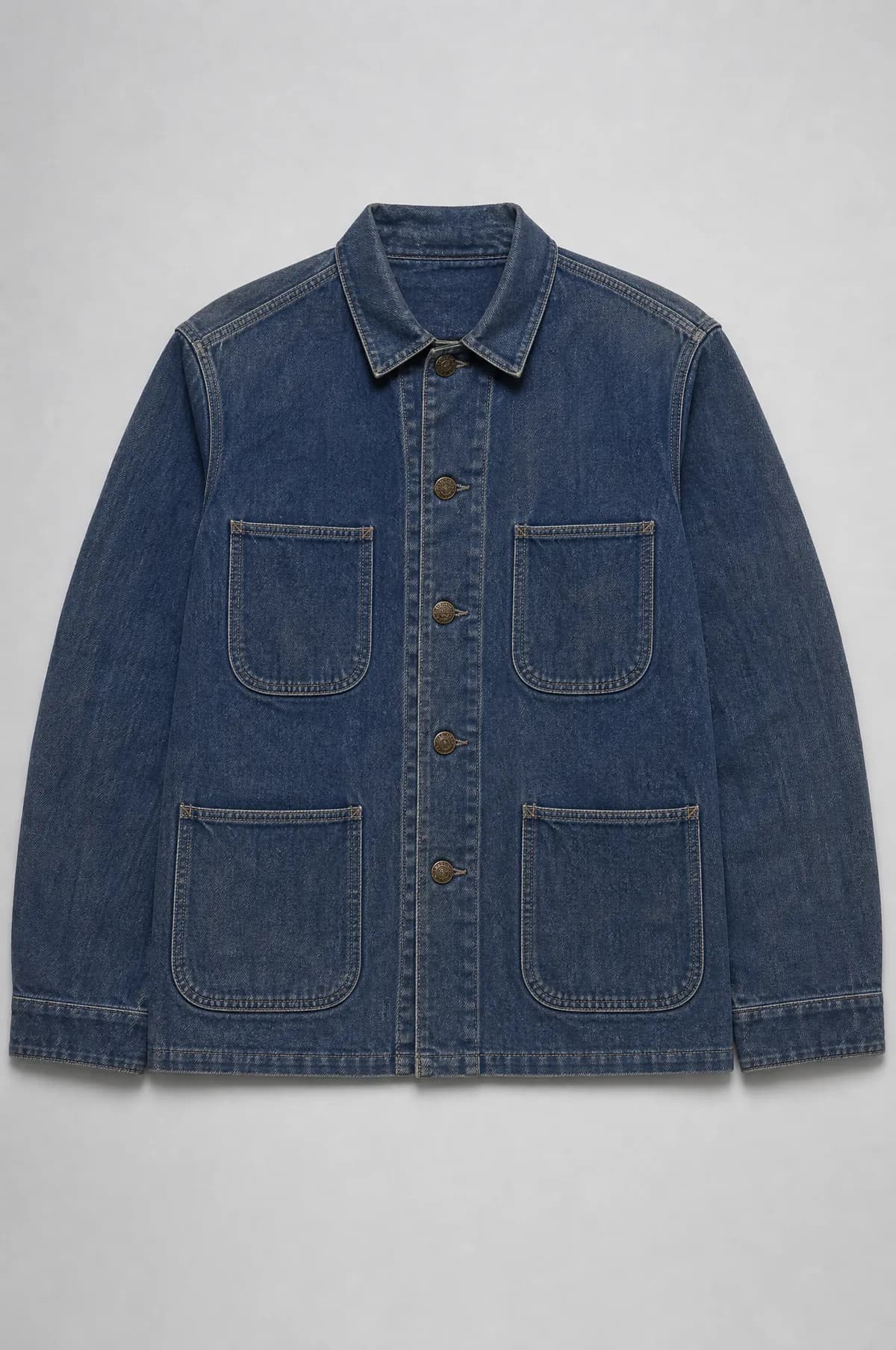 A faded indigo cotton work jacket laid flat with four patch pockets and heavy topstitching.
