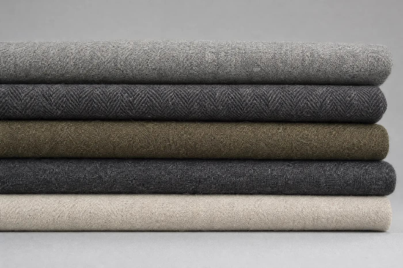 Five folded wool cloths seen edge on, the folded edges forming horizontal bands.