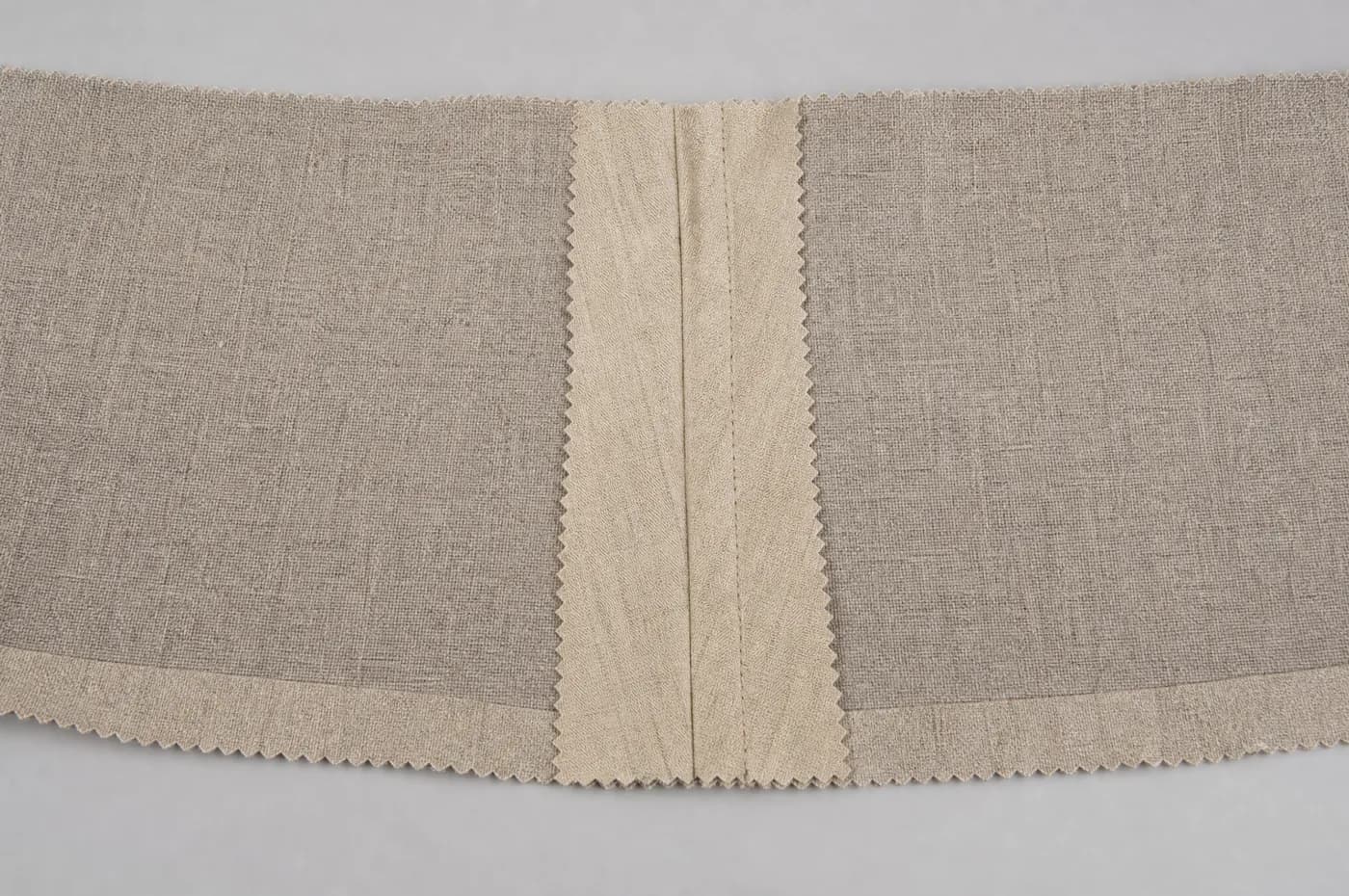 A trouser seam opened flat and pressed, showing machine stitching and pinked raw edges.