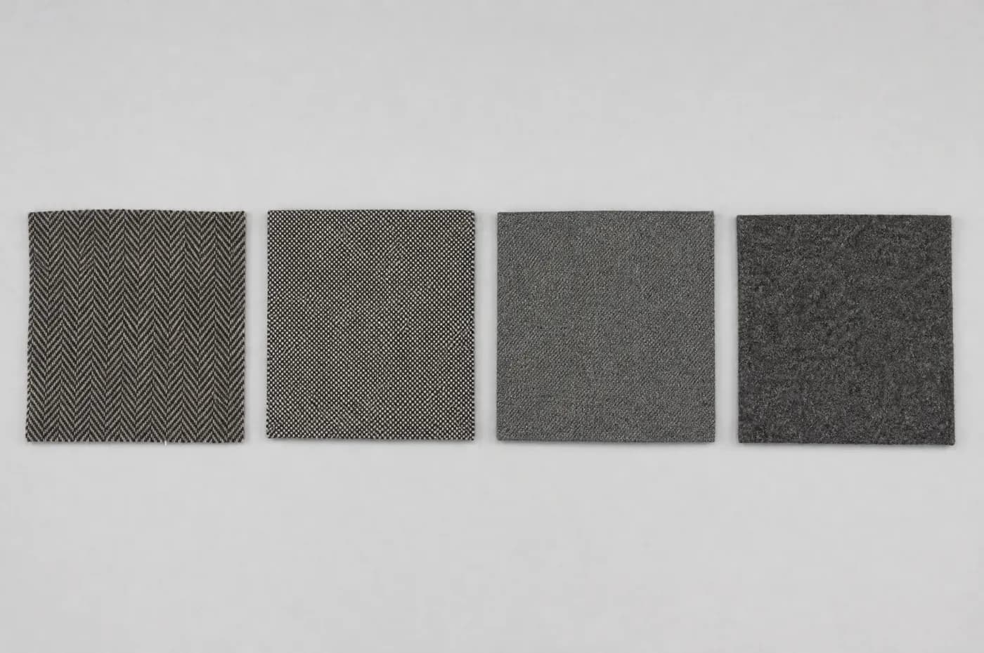 Four squares of suiting cloth laid side by side: herringbone, birdseye, sharkskin and flannel.